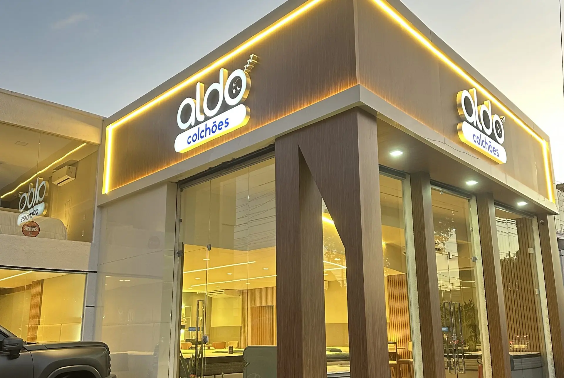 Fachada da loja Aldo Colchões em Fortaleza ao anoitecer